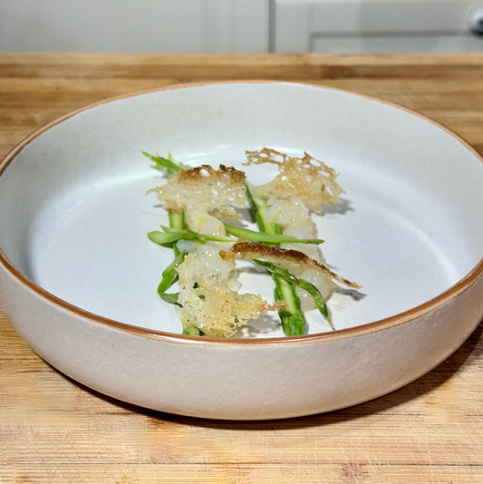 Tartare di scampi con asparagi croccanti, chips di pane e zenzero fresco, servita come antipasto gourmet con olio extravergine di oliva italiano.