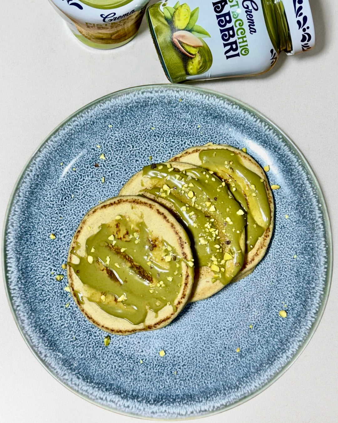 cakes soffici all’albume con crema al pistacchio e granella, su piatto bianco – ricetta fit e gourmet di Chef Oscar Pisterzi.